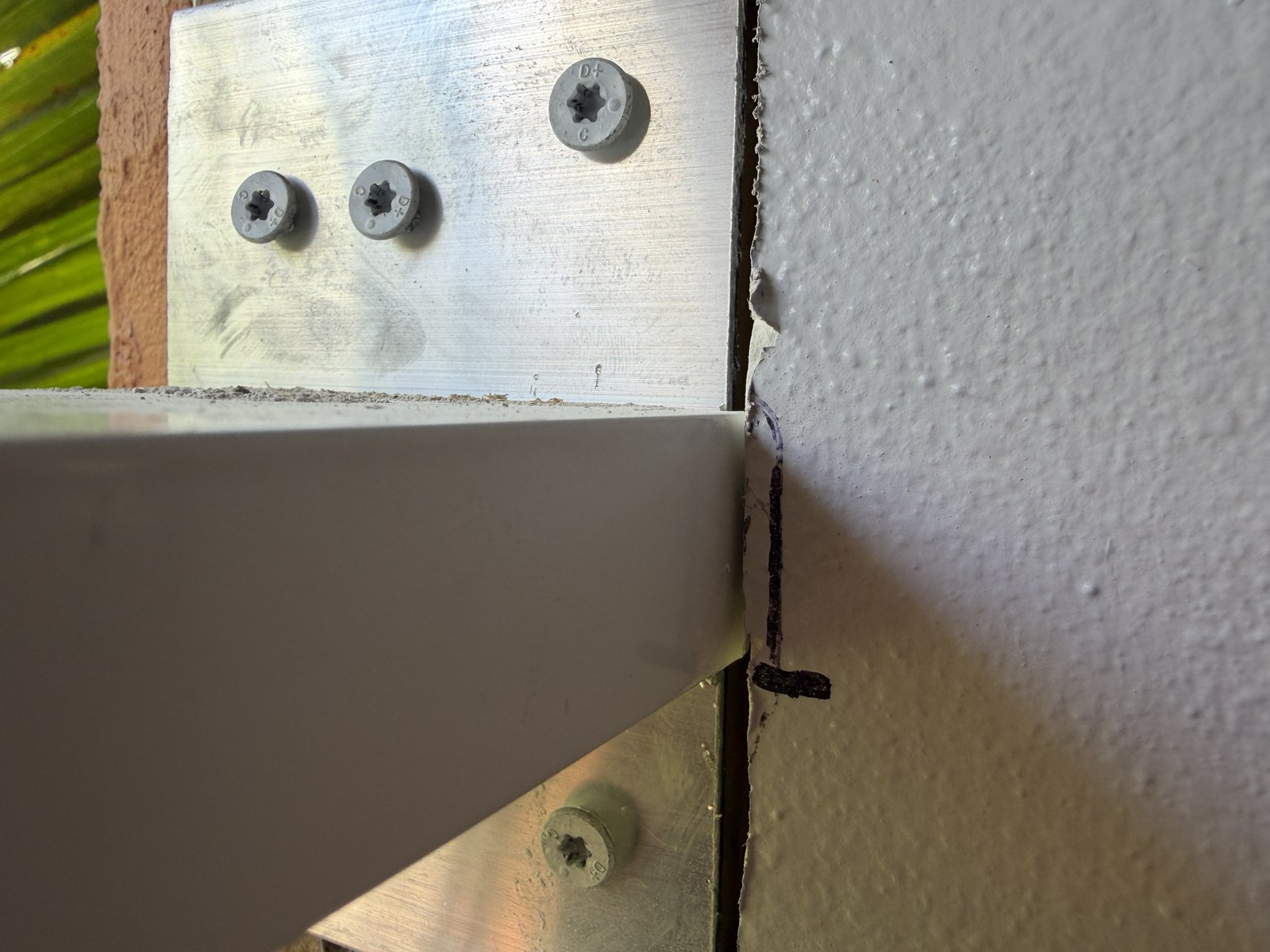 Close-up of an aluminum mullion anchor clip fastened with screws