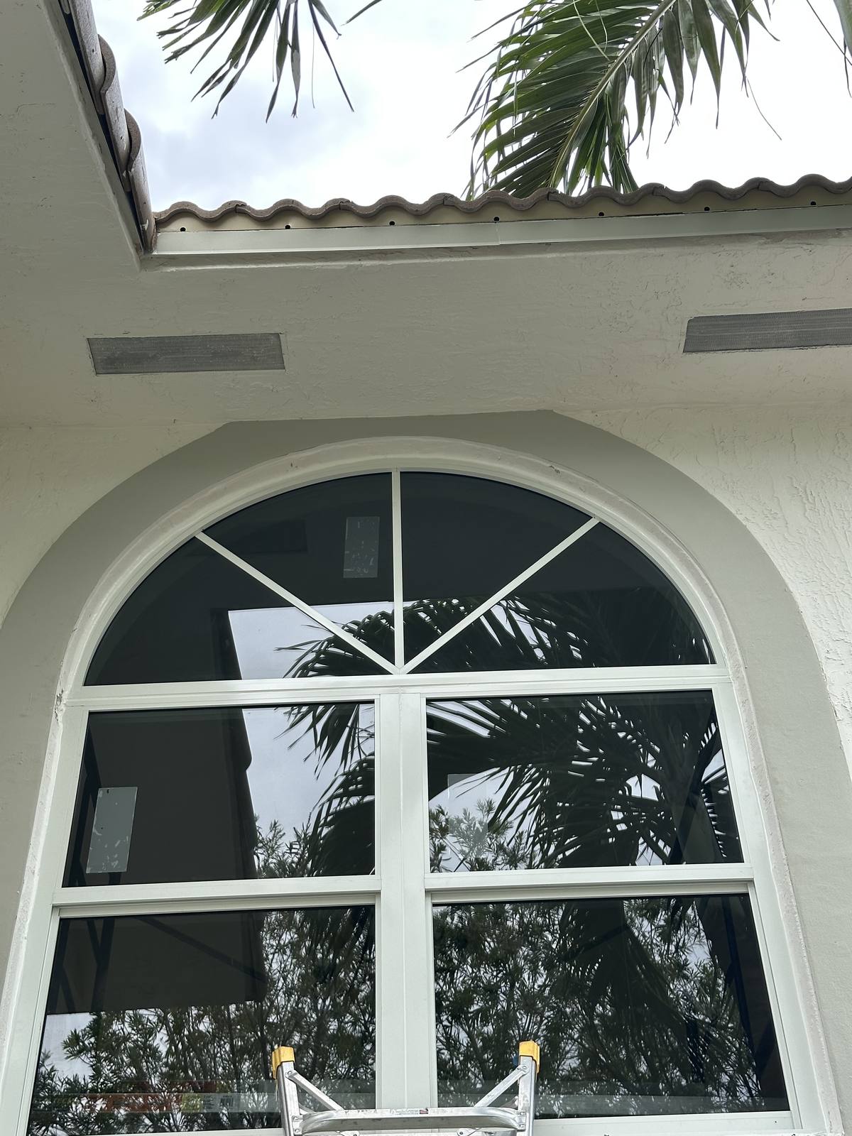 White arched impact window assembly with grids on a stucco home