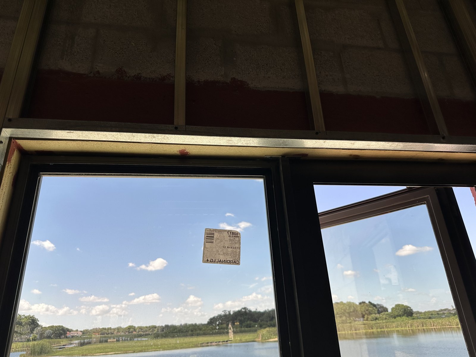 Dark-frame mulled impact windows installed with labels still on the glass, lake view