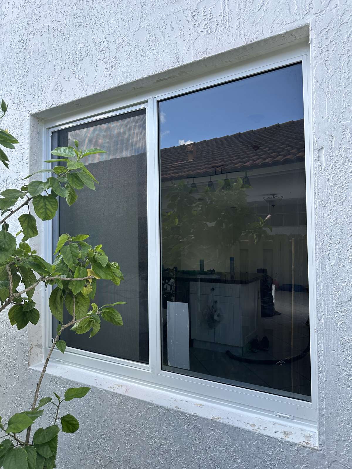 White horizontal rolling impact window installed on a stucco wall, South Florida home