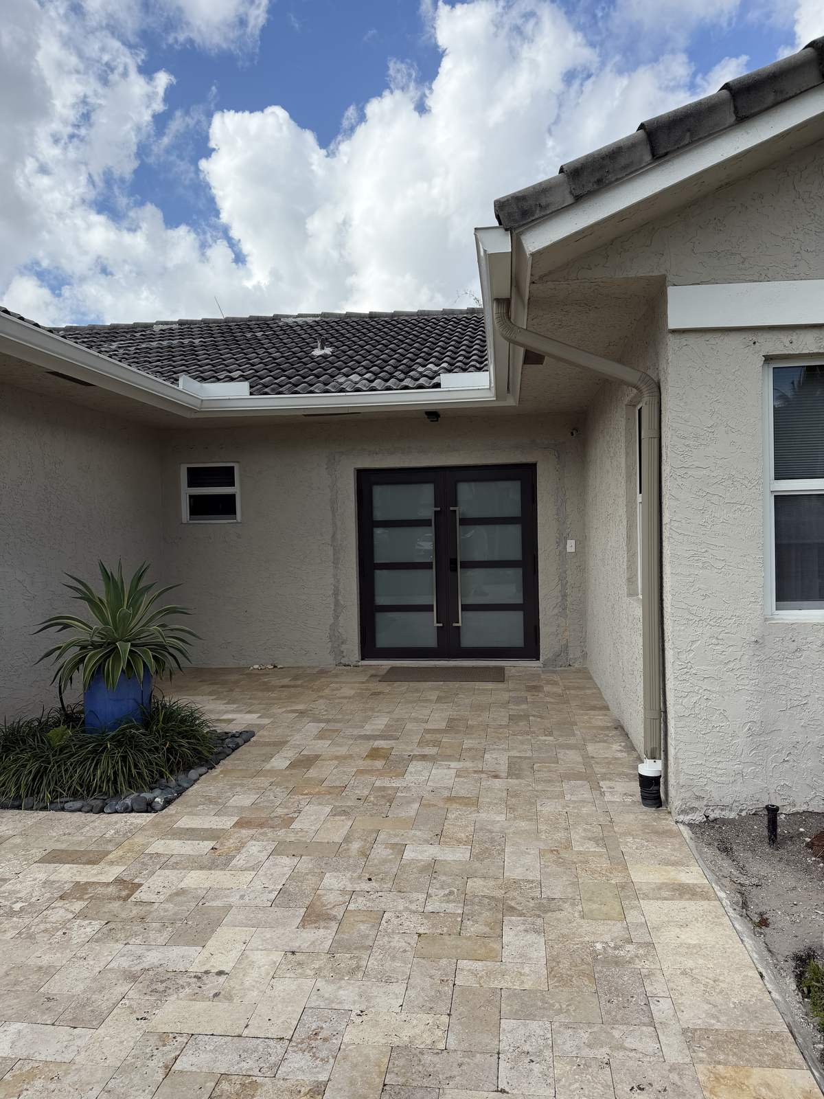 Bronze double impact entry doors with frosted glass at a paver courtyard entrance