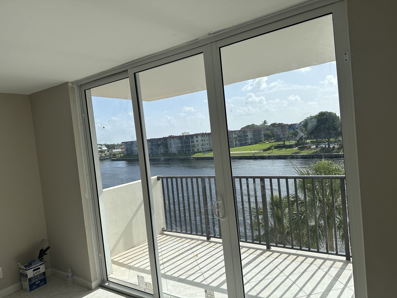 White three-panel impact sliding glass door opening to a condo balcony