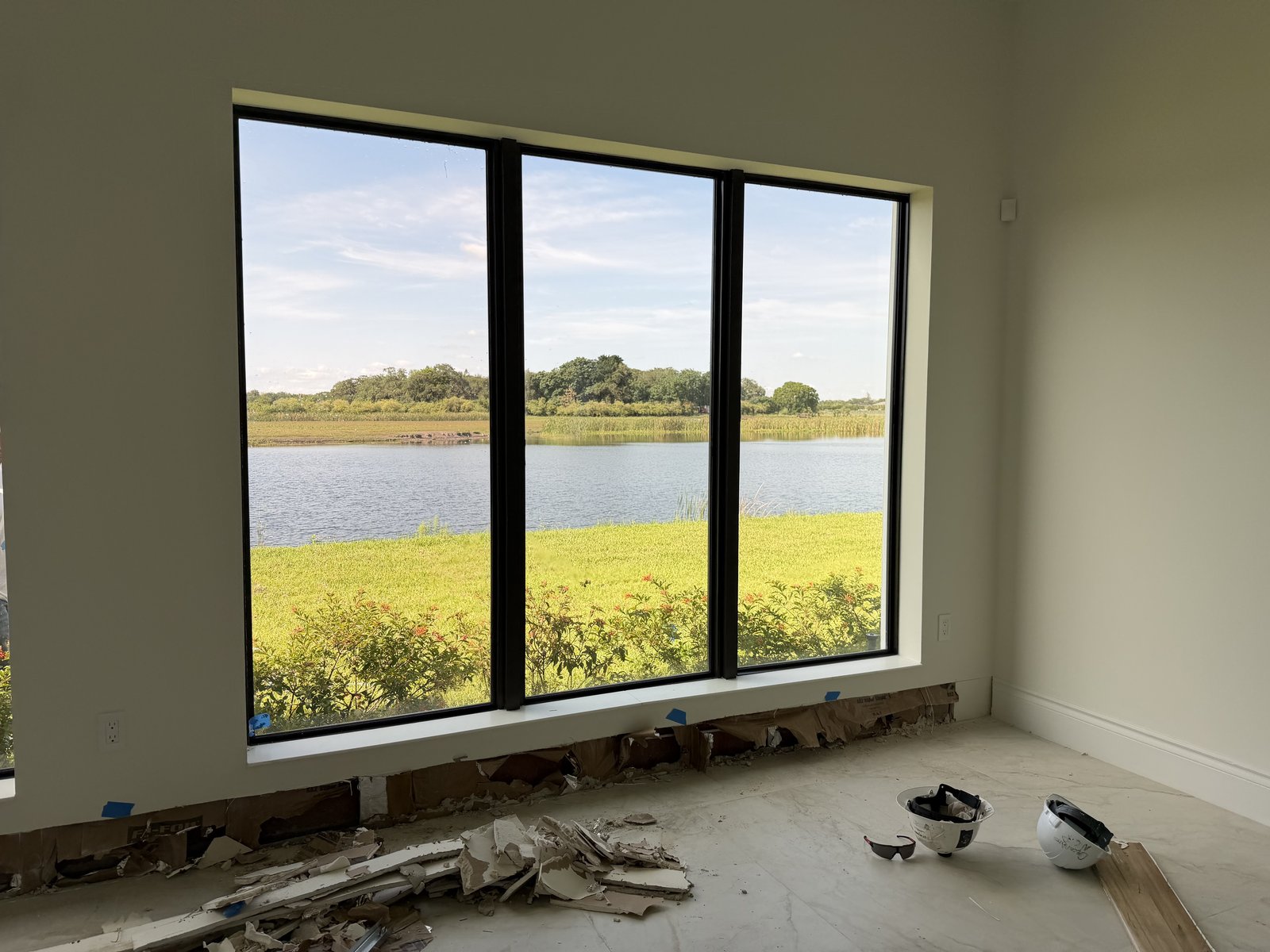 Black-frame fixed impact windows overlooking a lake in a new home