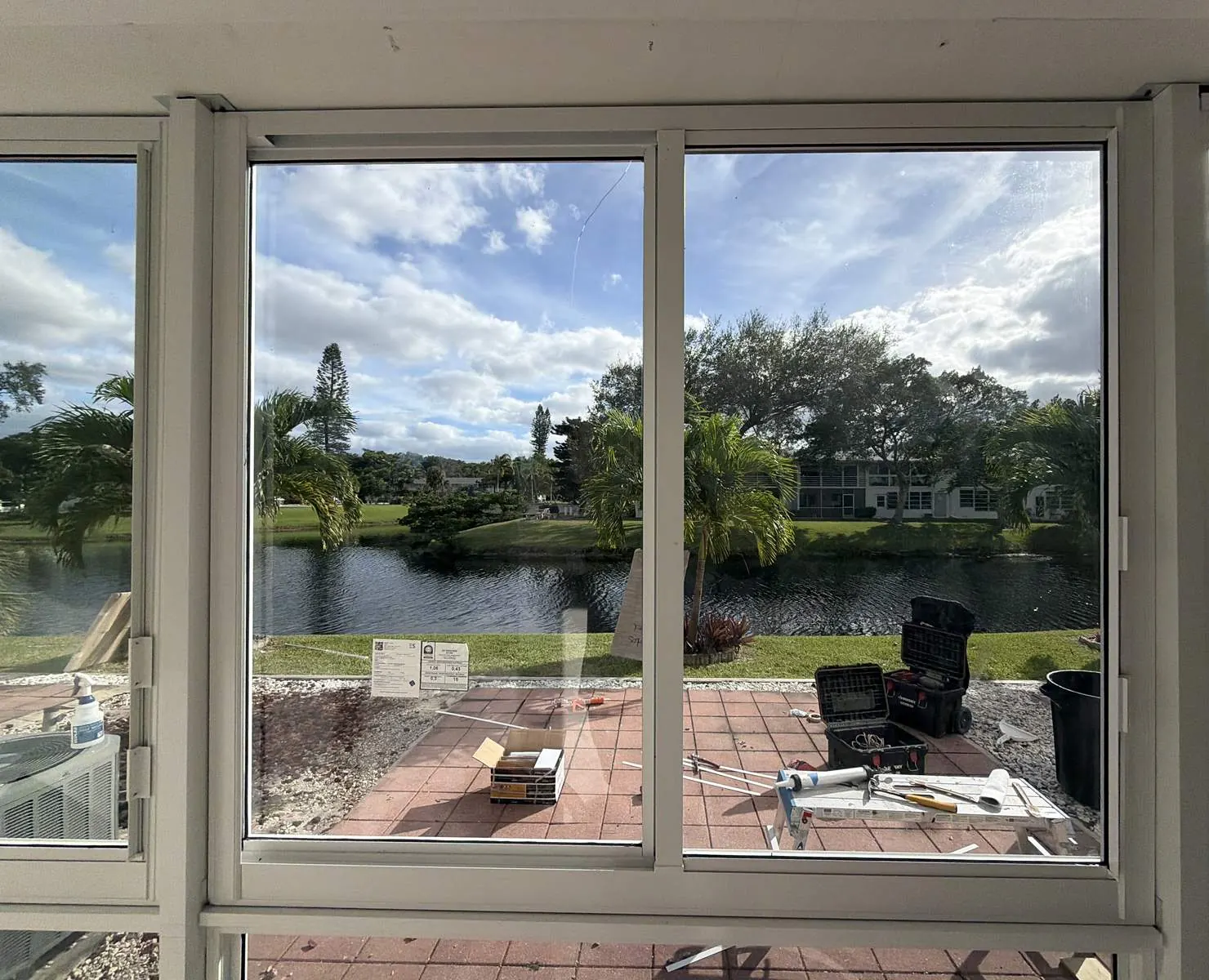 White horizontal rolling impact windows in a patio enclosure with a lake view