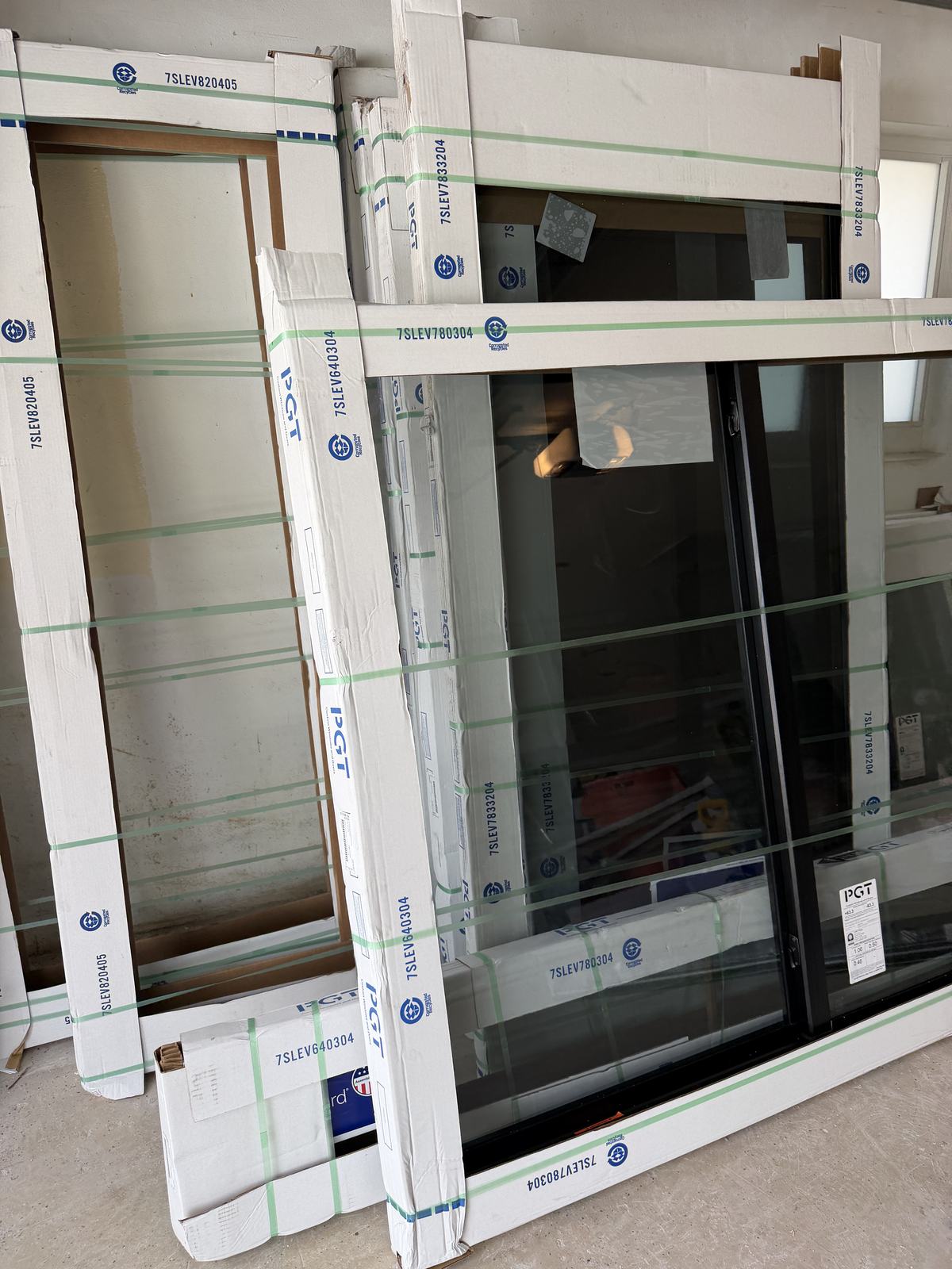 PGT impact windows in protective packaging staged at a jobsite